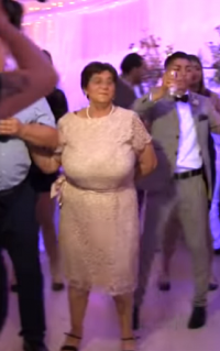 Brunette Super Busty Grandmama with Huge Boobs in a Sexy White Dress and Black Heels Dancing a...png